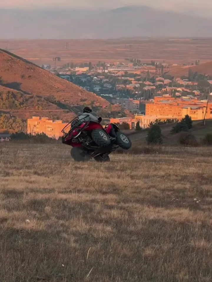 ATV on a hillside above the town at sunset