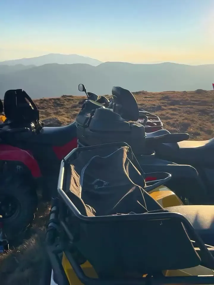 ATVs parked on a mountain ridge at sunset